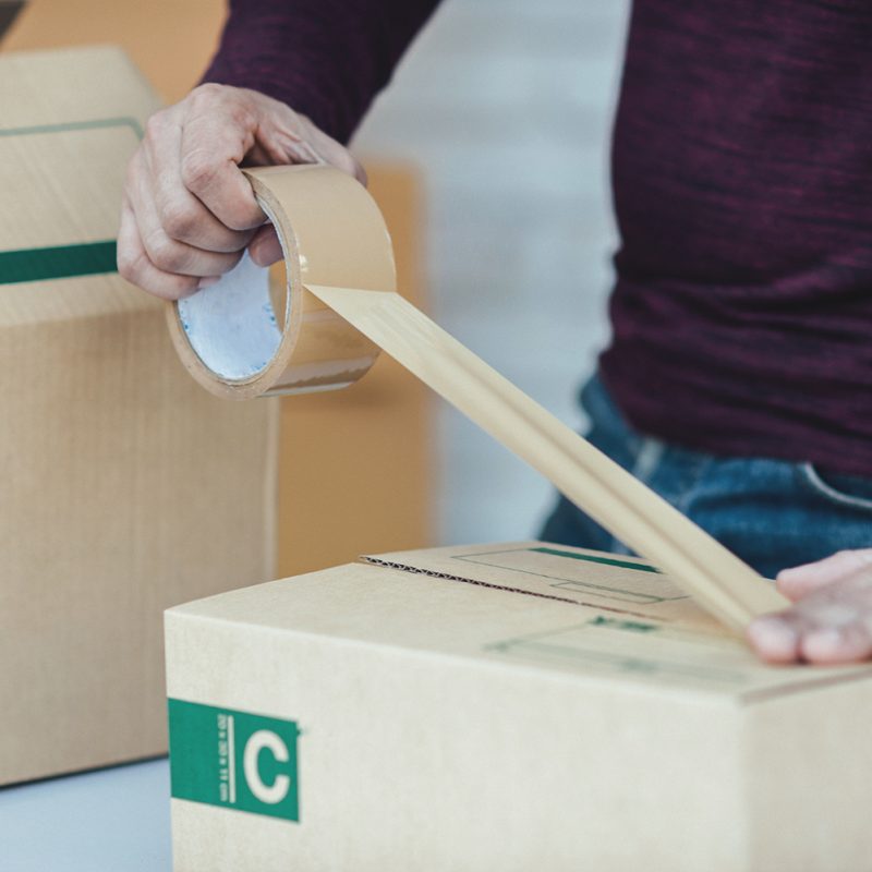 Handsome Young man working with papers among parcels at table in delivery department. online concept